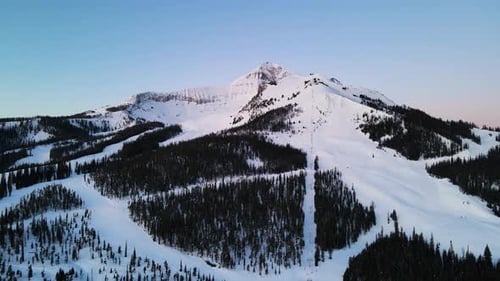 A drone shot of snowy Big Sky, Montana in winter, showcasing the ski resort and majestic mountain te