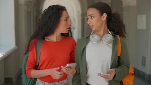 Dois estudantes, meninas, mulheres, amigos multirraciais, hispânicos, caminham no campus, caminham juntos em