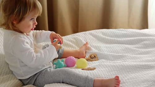 Child Plays with Toys on Bed