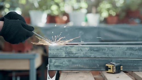 Worker welding metal framework with sparks in workshop