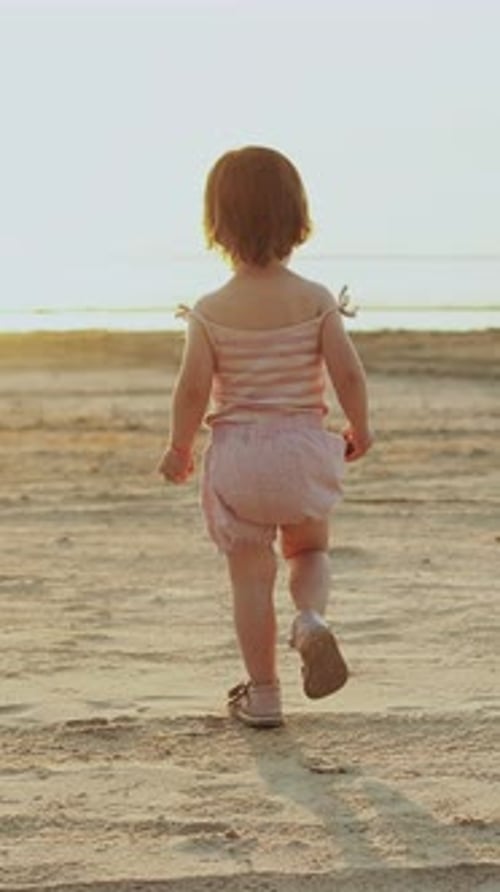A Toddler Joyfully Walking on the Beach at Sunset Creating Beautiful Memories with Family Vertical