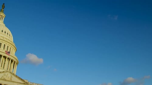 The white limestone of the United States Capitol building shines during sunrise as the camera pans l