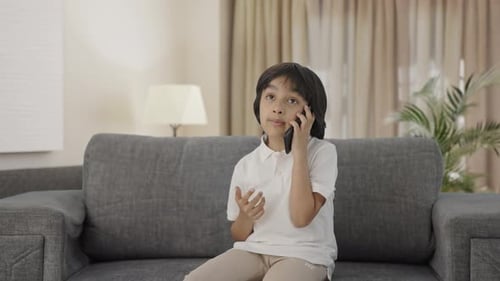 Boy Talking on Phone Seated on Sofa Indoors