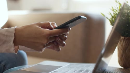 Unrecognizable Woman Texting on Smartphone Chatting in Social Media Sitting Near Laptop at Home Slow