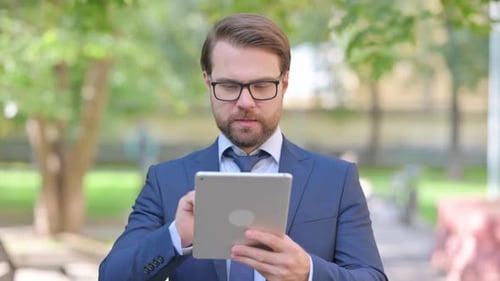 Adult Male Celebrating with a Tablet Outdoors