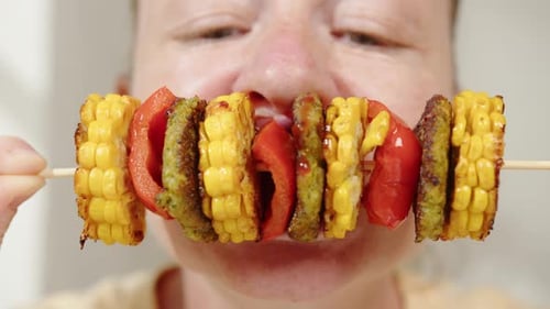 Femme végétalienne mordant et mangeant des légumes végétariens au barbecue sur une brochette