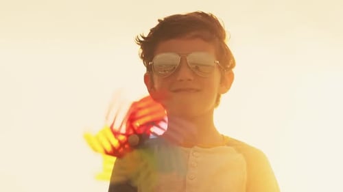 Smiling Boy Holding Colorful Pinwheel in Sunset Light