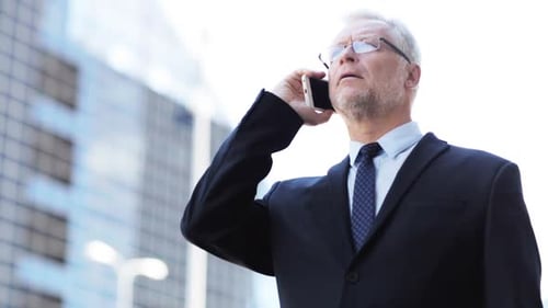Serious Businessman Talking on Phone in City