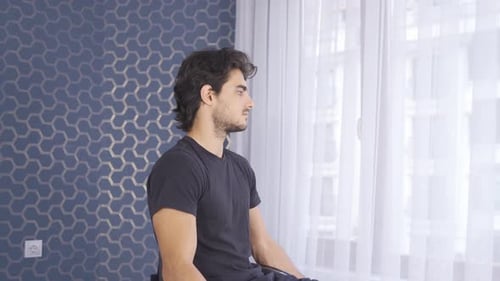 Unhappy disabled man looking out the window, feeling sad and helpless at home.