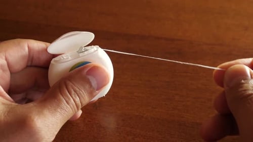 Person Pulling Dental Floss for Oral Hygiene