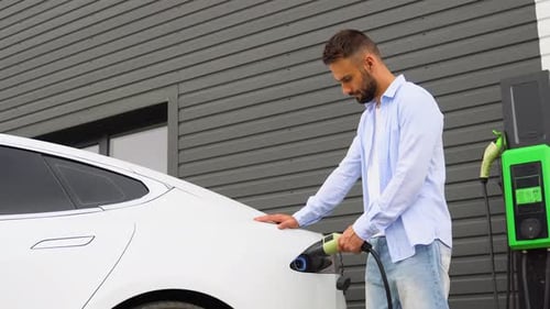 Man Charging Electric Car at Charging Station