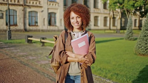 Smiling Student Holding Notebook on Campus