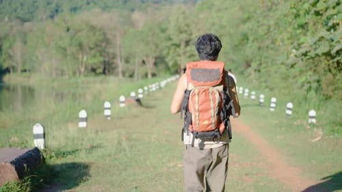 Young travel asian man walking on trail up peaceful lush high elevation green forest