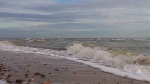 Slow Motion of Sea Waves Washing Northern Sandy Beach with Water and Foam Camera Moves Along Stormy