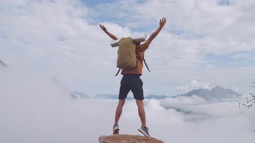 Asian Hiker Male Jumping Happy And Raising His Hands Celebrating Reaching Up Top Of Foggy Mountain