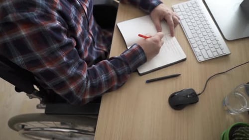 A Disabled Worker Sitting in a Wheelchair Works at a Computer