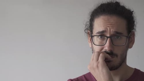 Close up with copy space of anxious man biting his nails and looking at camera