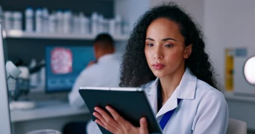 Scientist Analyzing Data on Tablet in Modern Lab