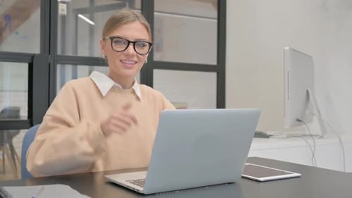 Smiling Woman Giving Thumbs Up While Working on Laptop