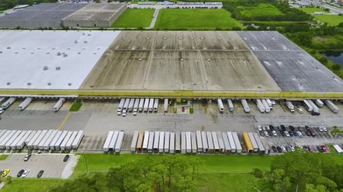 Aerial View of Large Commercial Loading Bay with Many Delivery Trucks Unloading and Uploading Retail