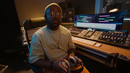 Portrait of Black Male Music Producer Posing in front of Mixing Desk in Studio