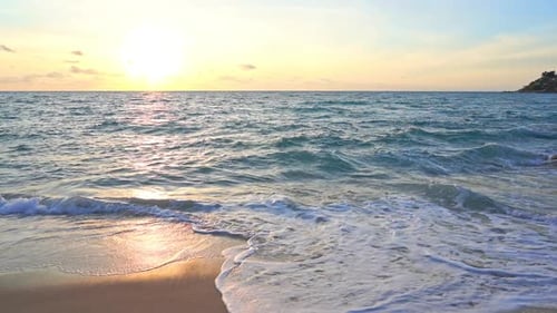 Slow-motion of waves crashing on beach and sunlight reflections on sea surface. Static view