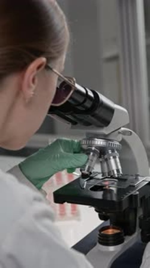 Woman Scientist Using Microscope in Laboratory Setting