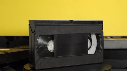 Rotating old VHS cassettes on a yellow background. retro video cassettes.