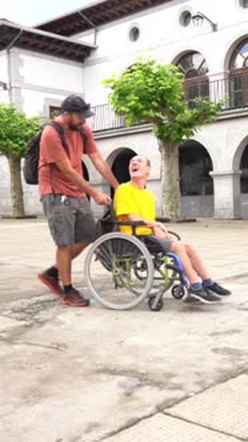 A disabled person in a wheelchair walking through the town square with a friend