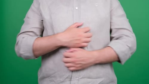 Man Rubbing his Abdomen Against Green Background