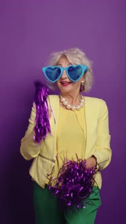 Senior Woman Dancing With Pom-Poms and Heart Glasses
