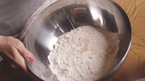Overhead view of pouring water into organic flour for artisan dough