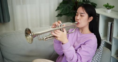 Young Woman Playing a Silver Trumpet at Home