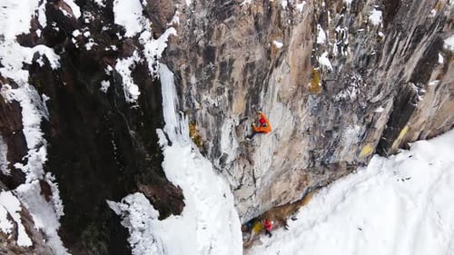 Ice Climber Ascends Frozen Rock Face in Winter