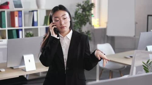 Asian Female Having Phone Conversation at Open Space Office