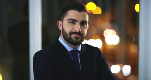Face, confident and business man in office, working at night on deadline in workplace and bokeh