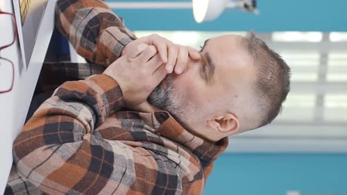 Tired Man Rubbing Eyes at Computer