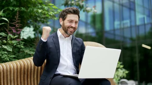 Successful Businessman Celebrates Good News on Laptop Outdoors