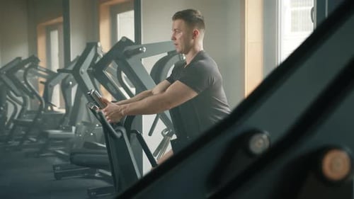 Middleaged Athletic Man Performs Exercises on Plate Loaded Seated Row Machine