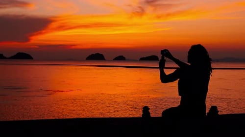 A videographer taking a magnificent sunset at a pier