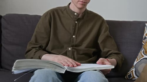 Young Adult Reading Book at Home on Couch