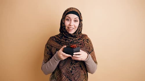 Surprised Muslim Woman in Hijab Receiving and Opening a Special Gift