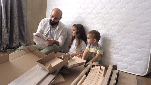Papa et enfants sont sur le sol en train de lire des instructions pour un nouveau lit dans la chambre des enfants