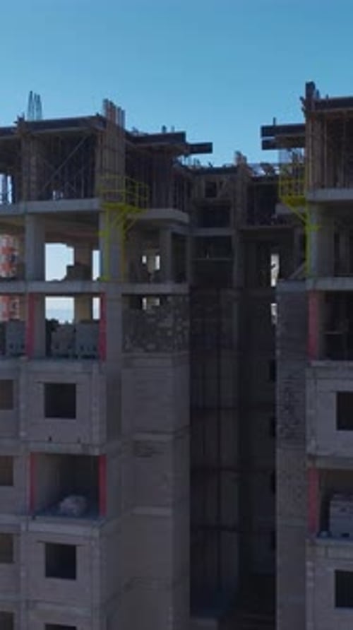 Vídeo vertical de ingenieros supervisando los planes de construcción mientras los trabajadores construyen paredes y una grúa