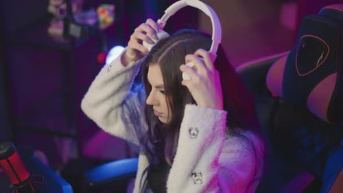 Woman Puts on Headphones in Gaming Room