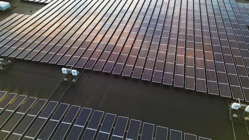 Sun reflection on large solar panel farm during sunset time. Aerial top down flyover. Modern install