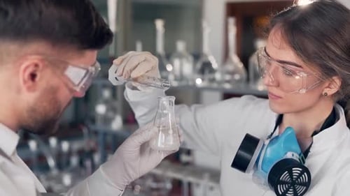 lab man and woman scientists in bathrobes are conducting a chemical experiment