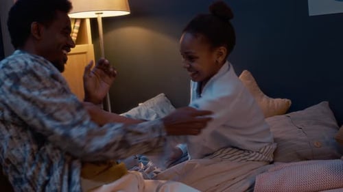 Child and Adult Play Clapping Game on Bed