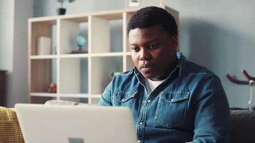 Close Up Face Concentrated African American Handsome Man Uses Computer for Work in Home Sit on Sofa