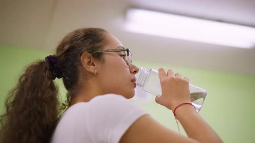 Close Side View Young Woman Drinking Water Indoors After Fitness Wellness Recovery